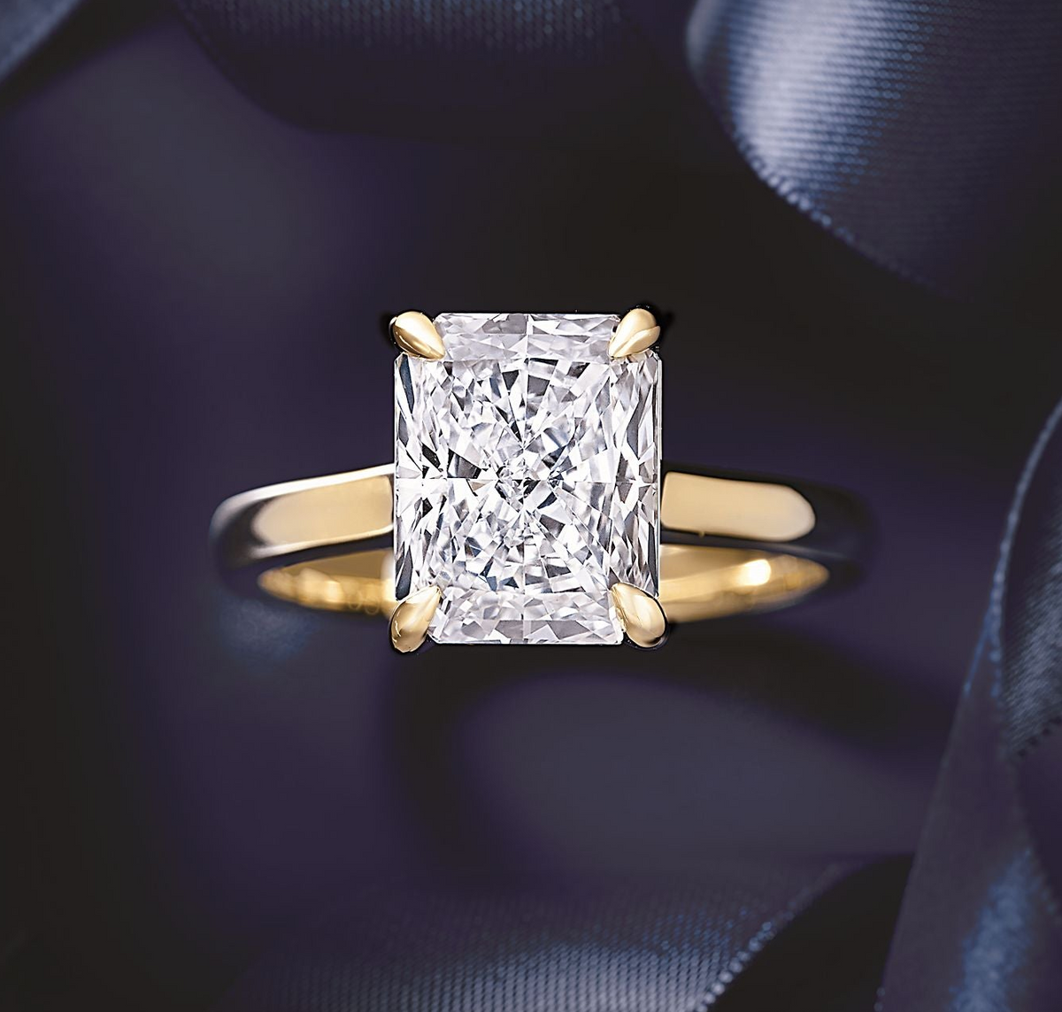 Gold ring with a large diamond on a dark blue satin background