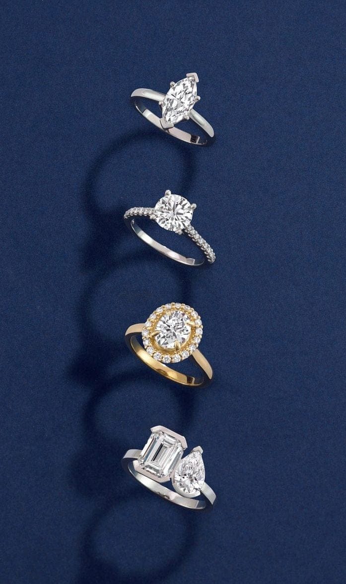 Four diamond engagement rings in different colors on a dark blue background
