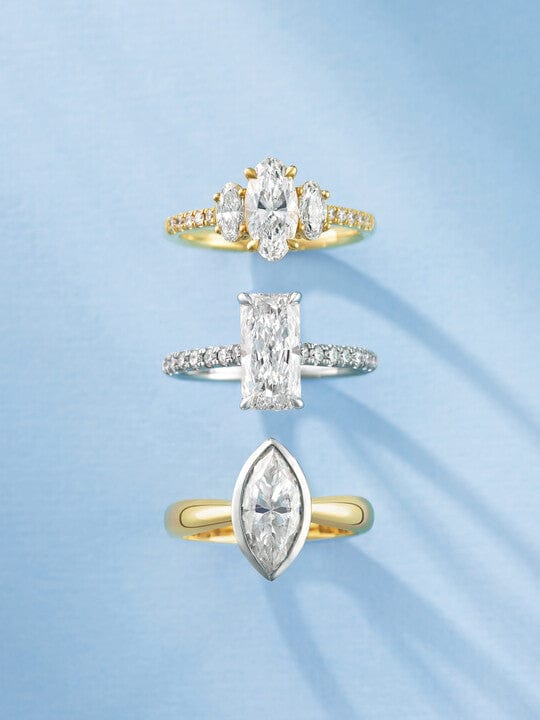 Three diamond engagement rings with different cut stones on a light blue background