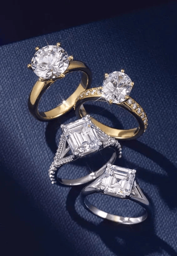 Set of diamond engagement rings on a dark blue textured background