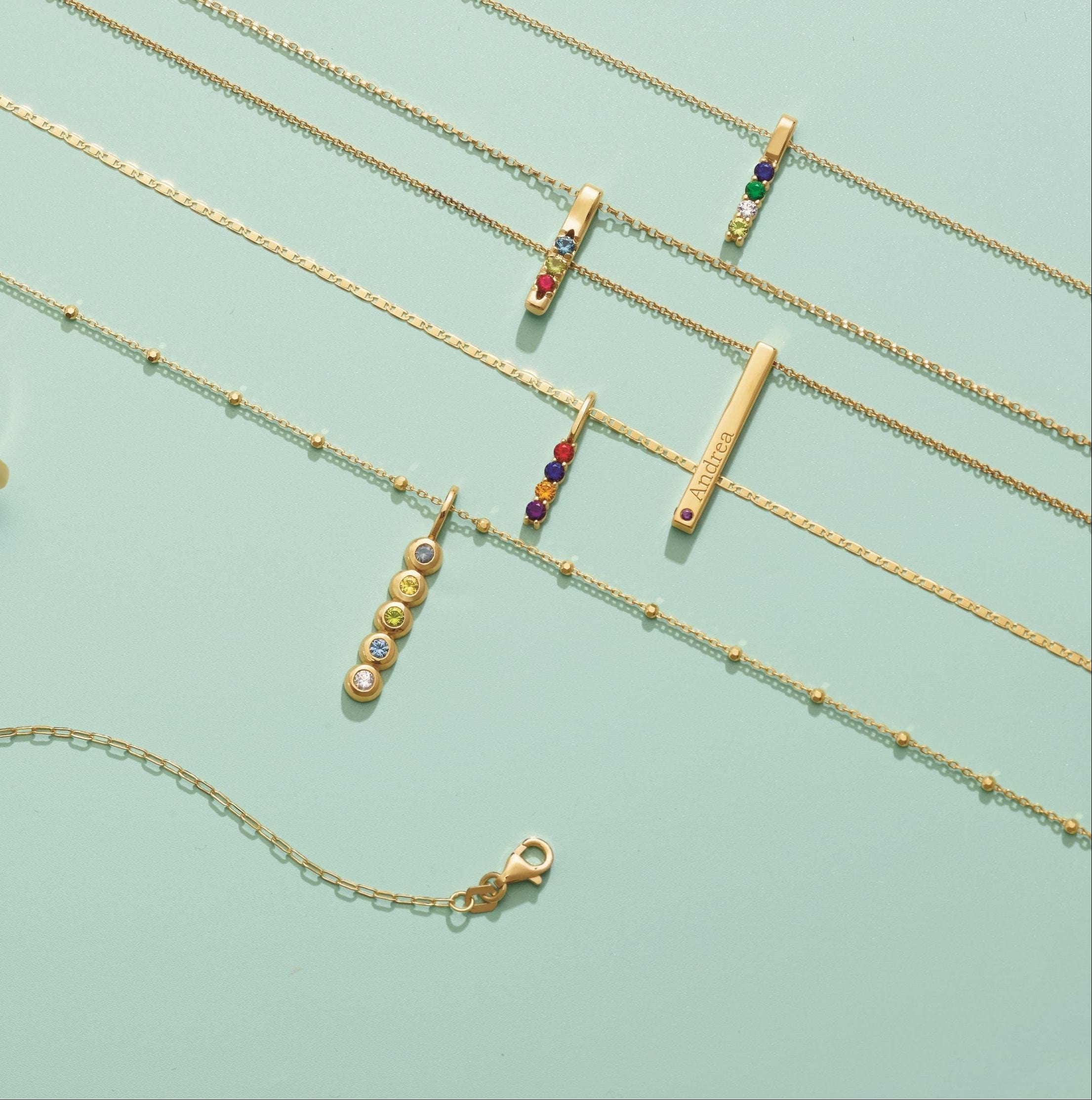 Gold gemstone jewelry set including necklaces, bracelets, and rings on a light green background