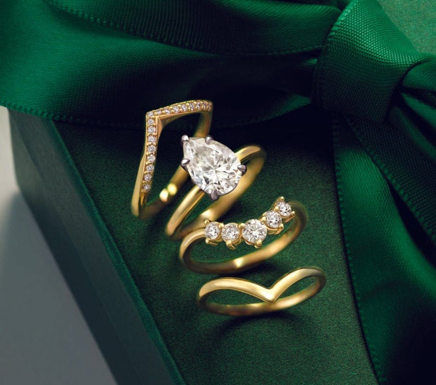 gold curved wedding bands wrapped around a pear shaped engagement ring