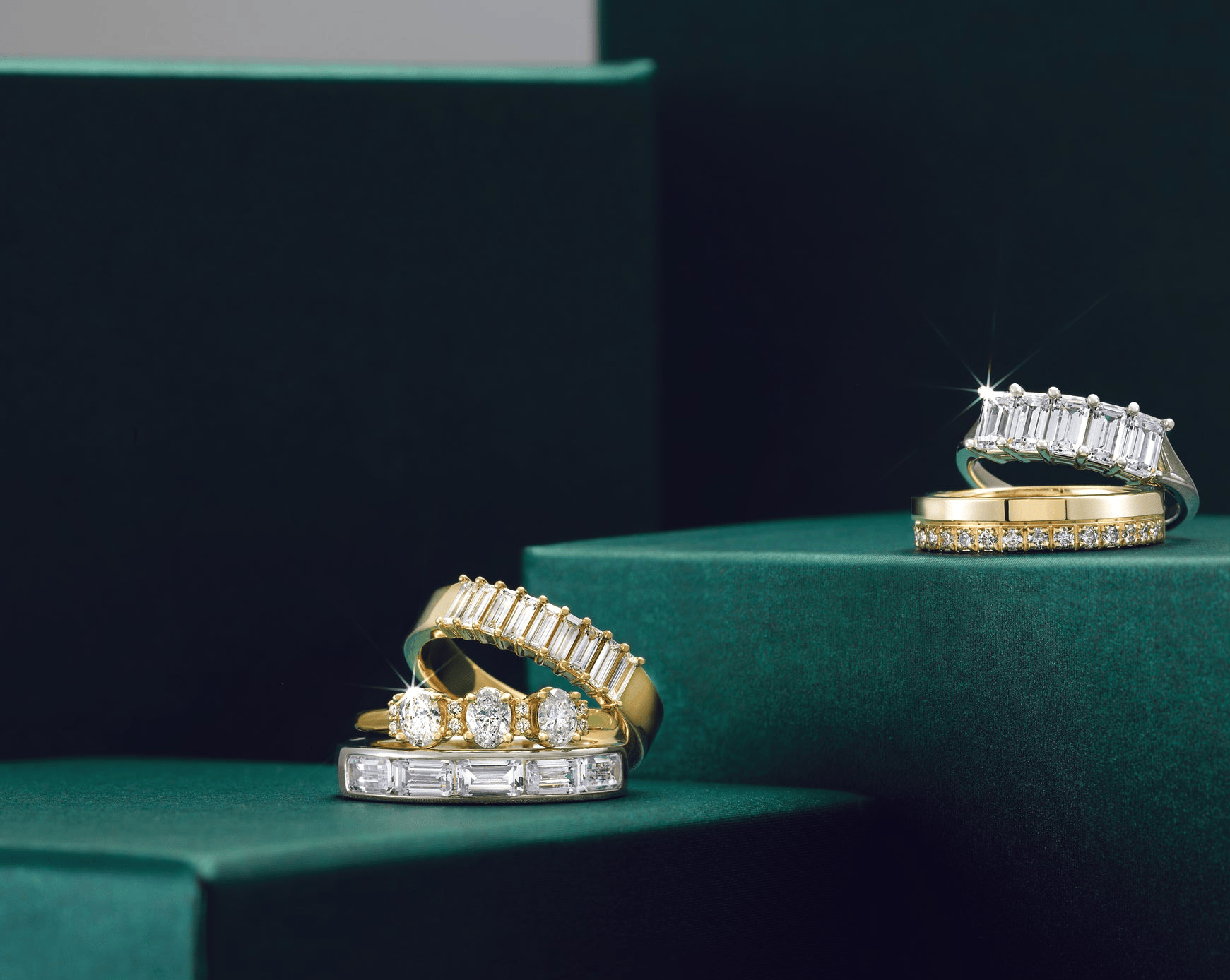 Gold rings with diamond accents on a green surface
