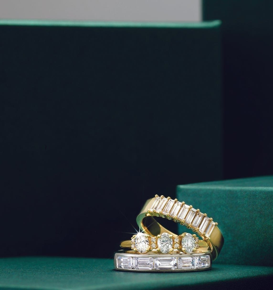 gold and diamond wedding rings laying on a green surface.