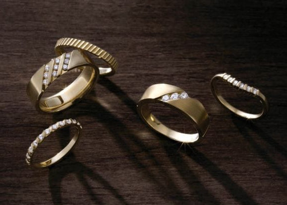 Gold wedding rings with diamond accents on a dark wooden surface