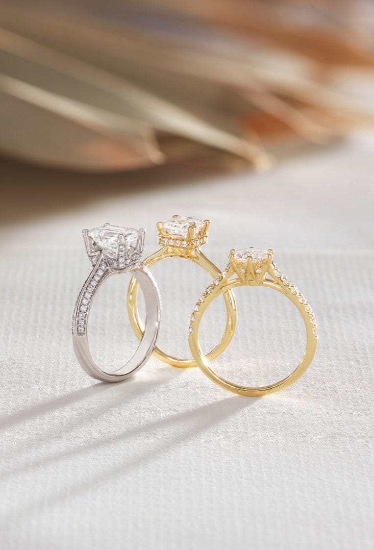 Three hidden halo diamond rings in gold and silver on a textured surface