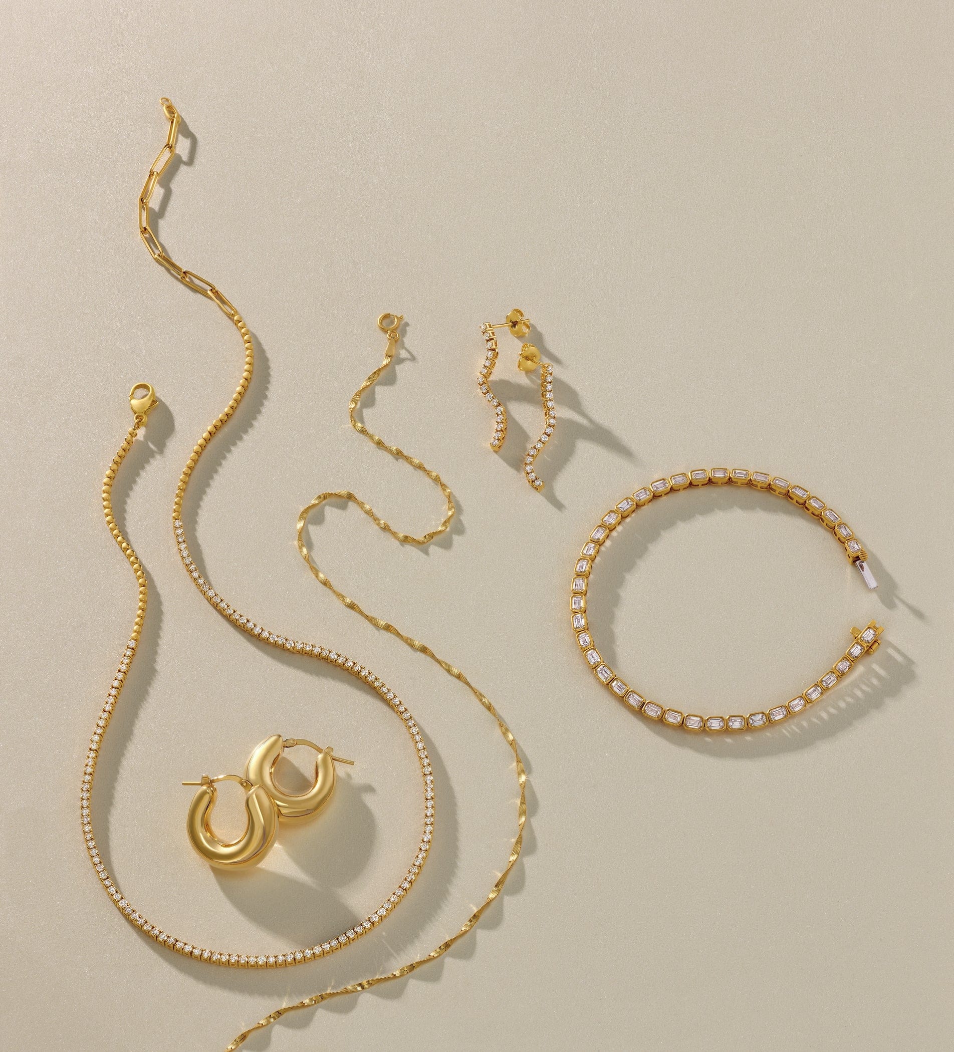 Gold fashion jewelry set including necklace, bracelet, and earrings on a light green background
