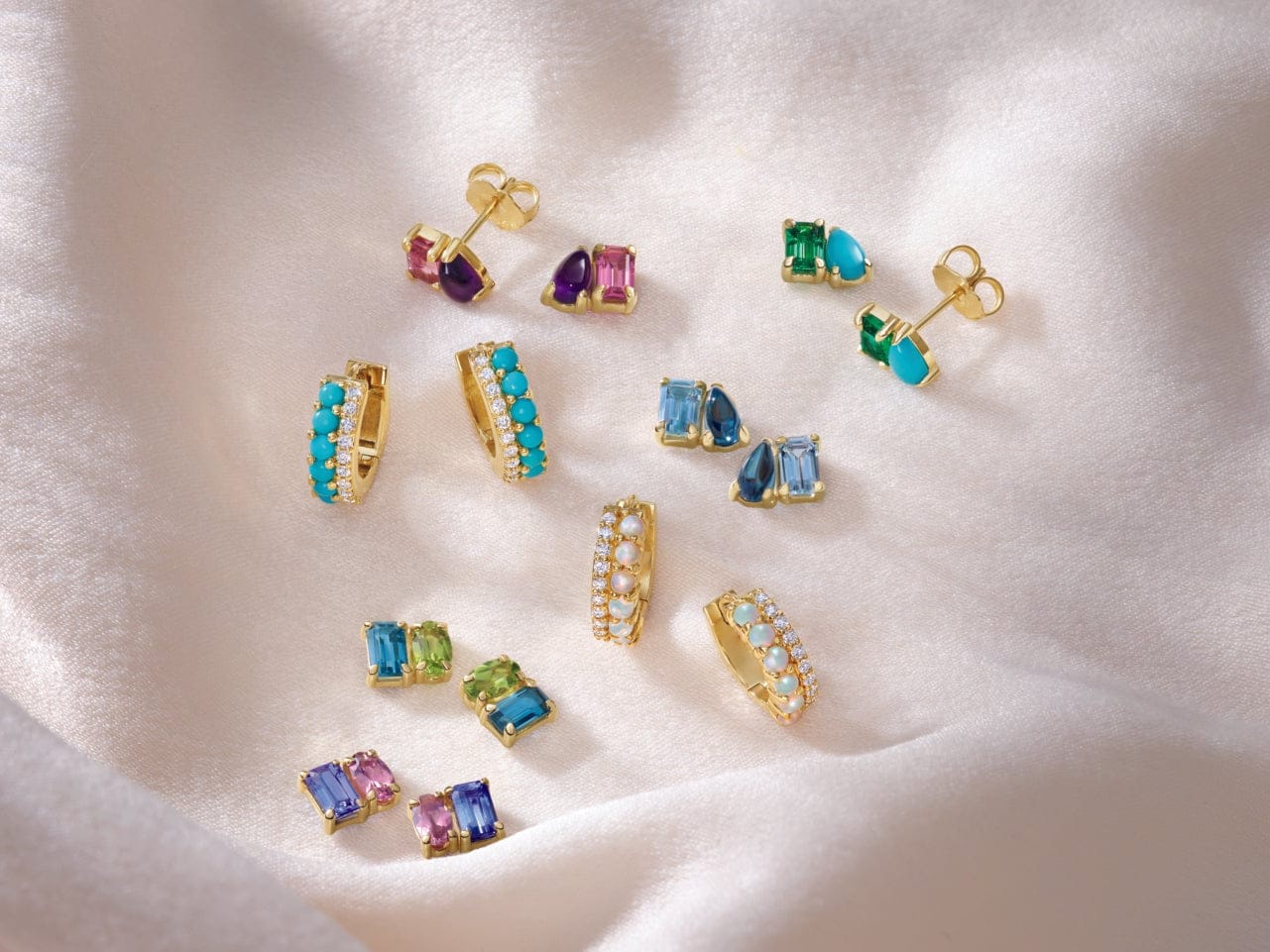 Colorful gemstone earrings on a soft white fabric background