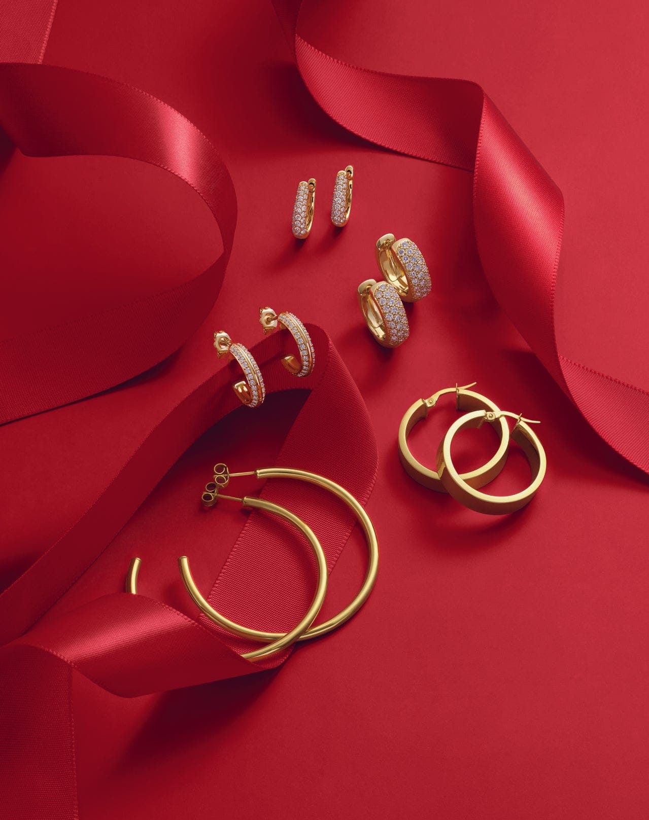 Gold and diamond earrings on a red fabric background