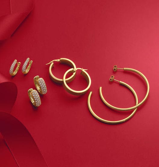 Gold jewelry including rings and a bracelet on a red background
