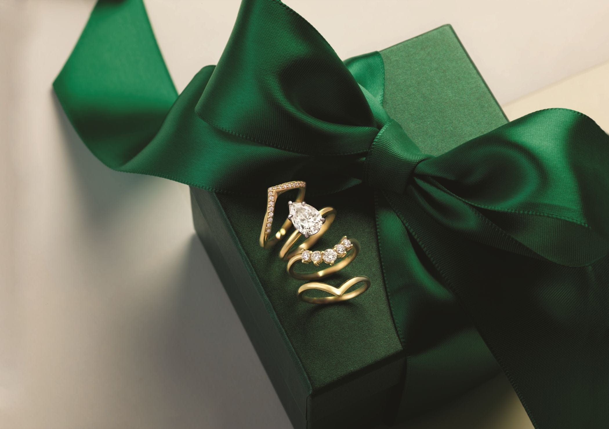 Gold DIAMOND ringS with diamonds on a green gift box with a bow