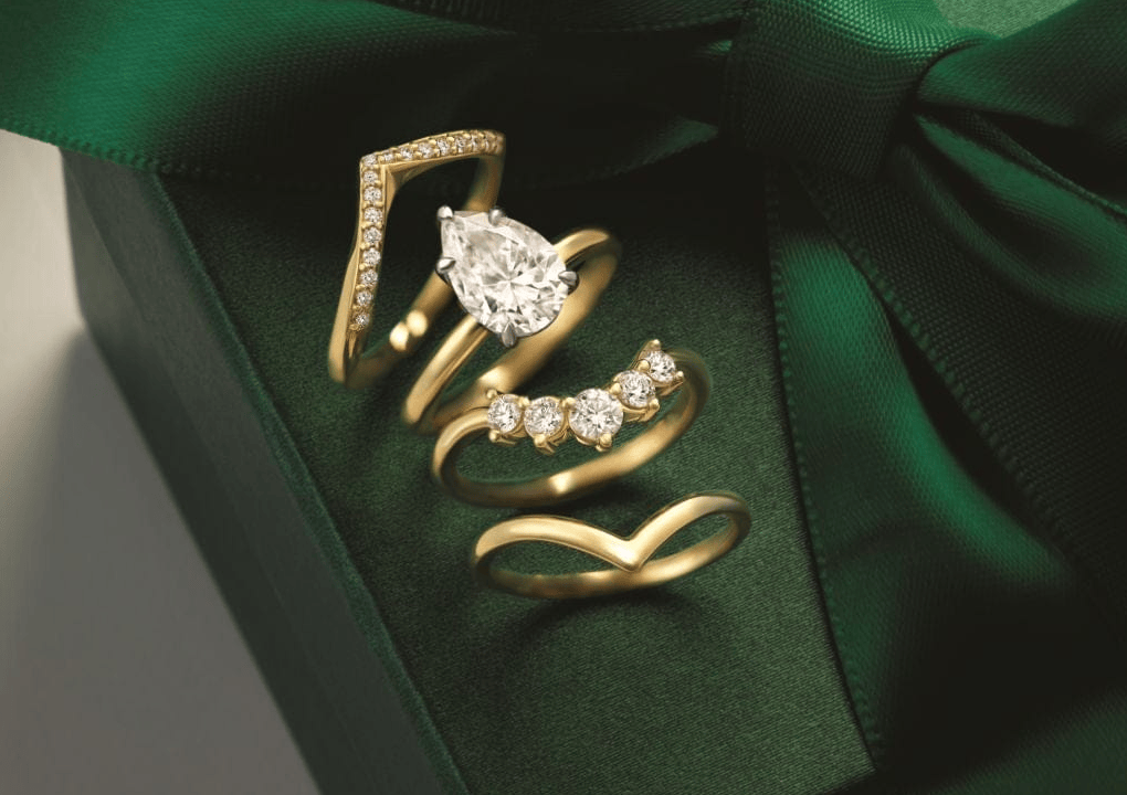 Gold engagement and wedding rings with diamonds on a green satin surface