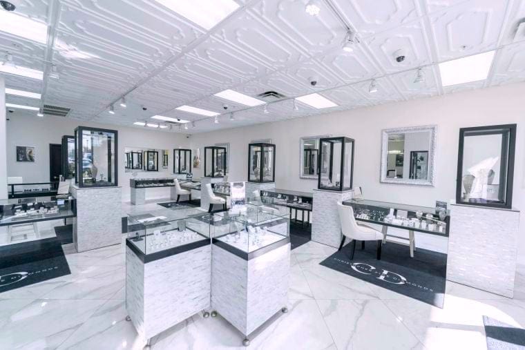Christopher Fine Diamonds' modern new jewelry store interior with white walls, marble floors, and glass display cases. 
