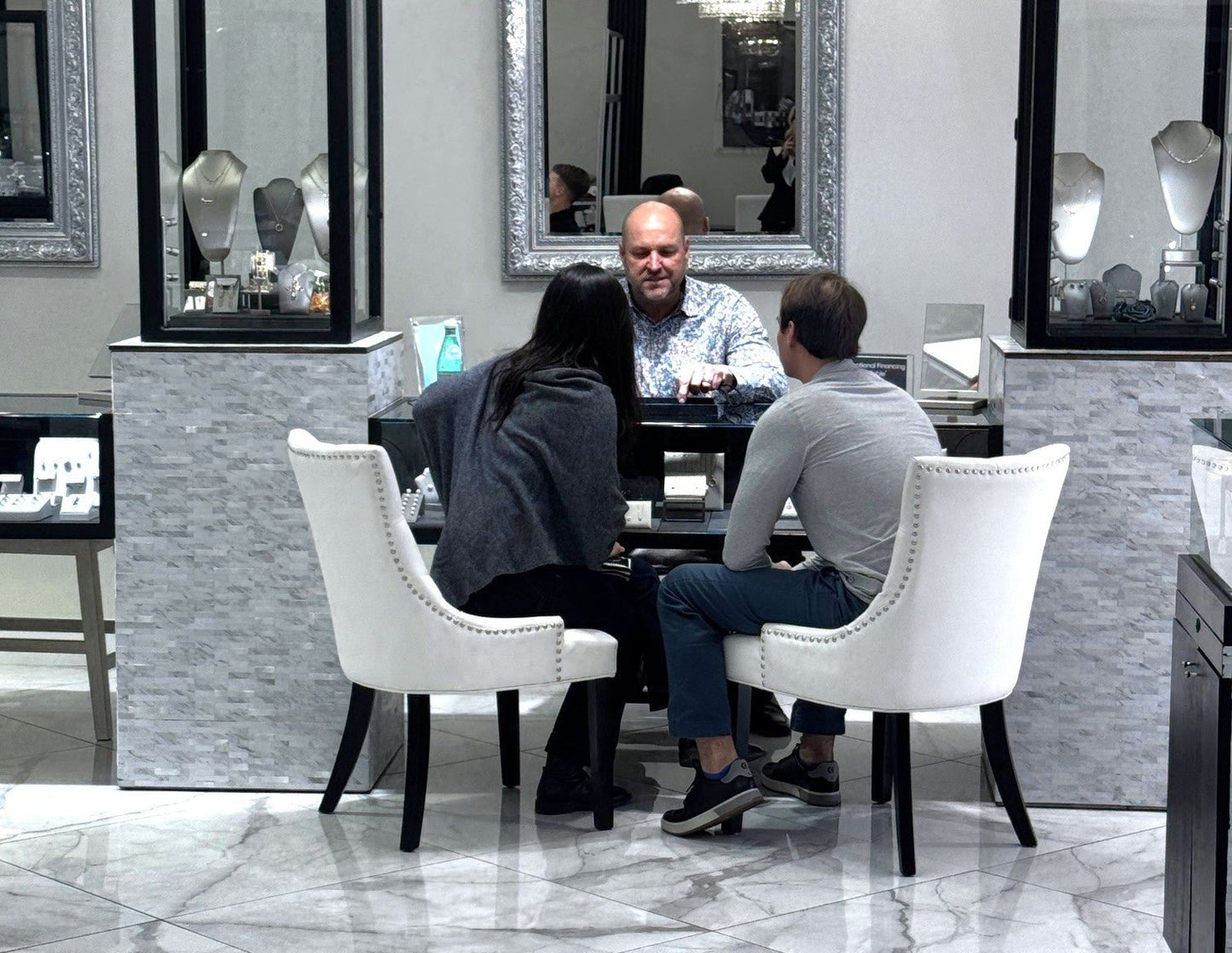 Jeweler consulting with a couple in a modern showroom during a private session for custom engagement rings and jewelry design.