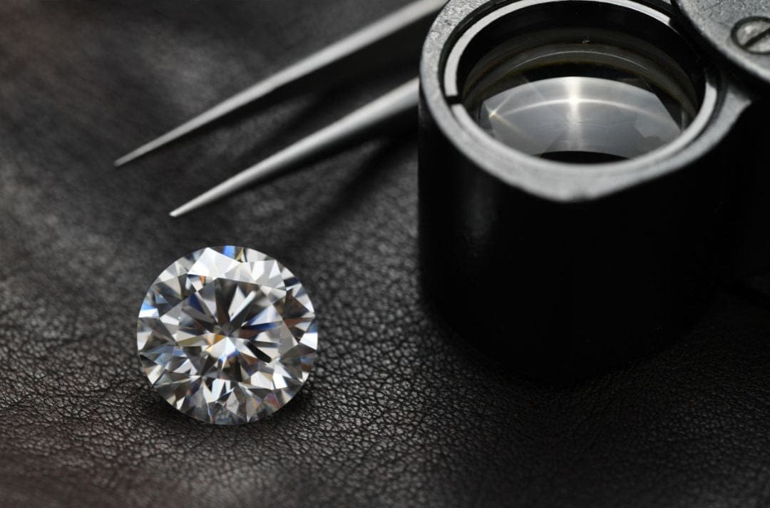Diamond on a dark surface with a loupe and tweezers