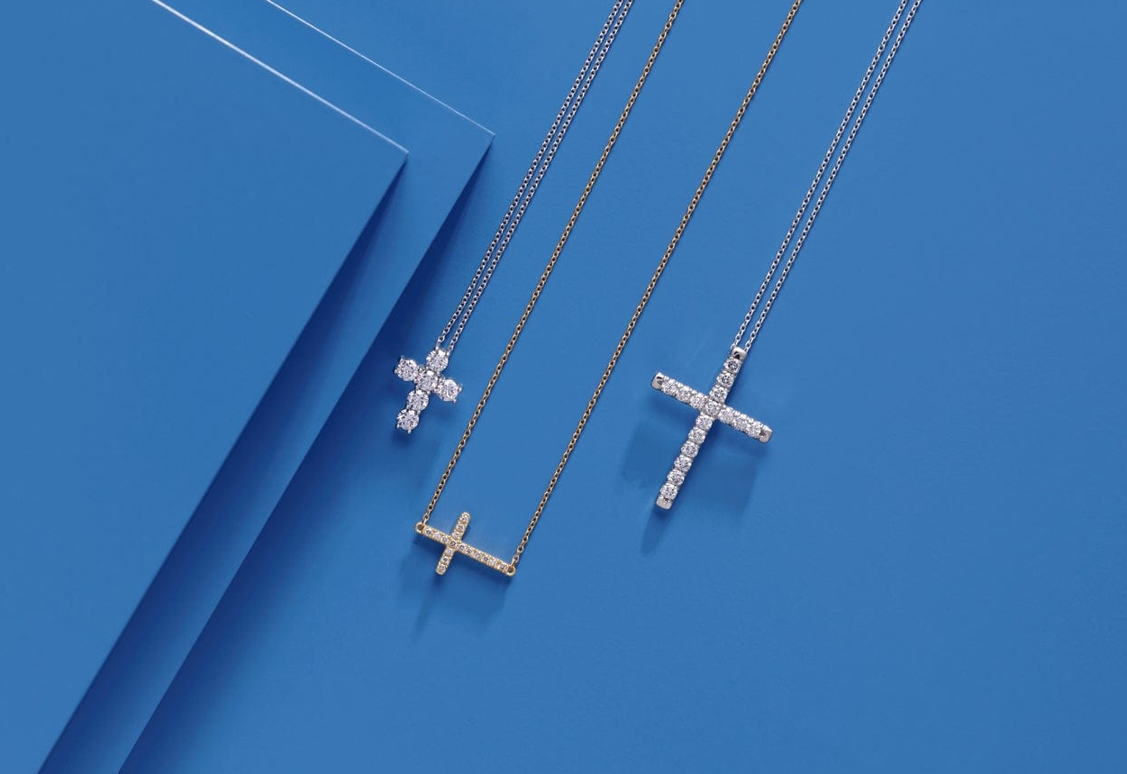 Two silver cross necklaces on a blue background