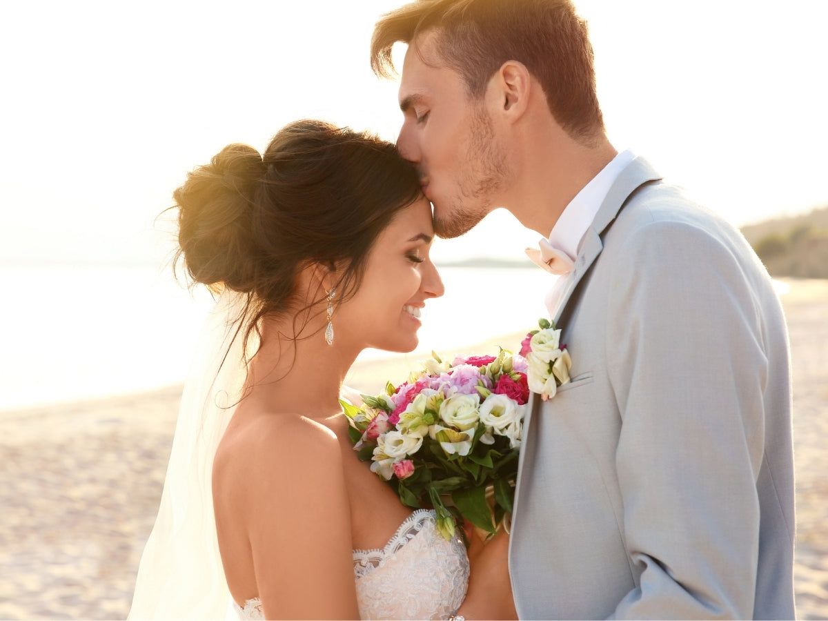 married couple kissing on the beach
