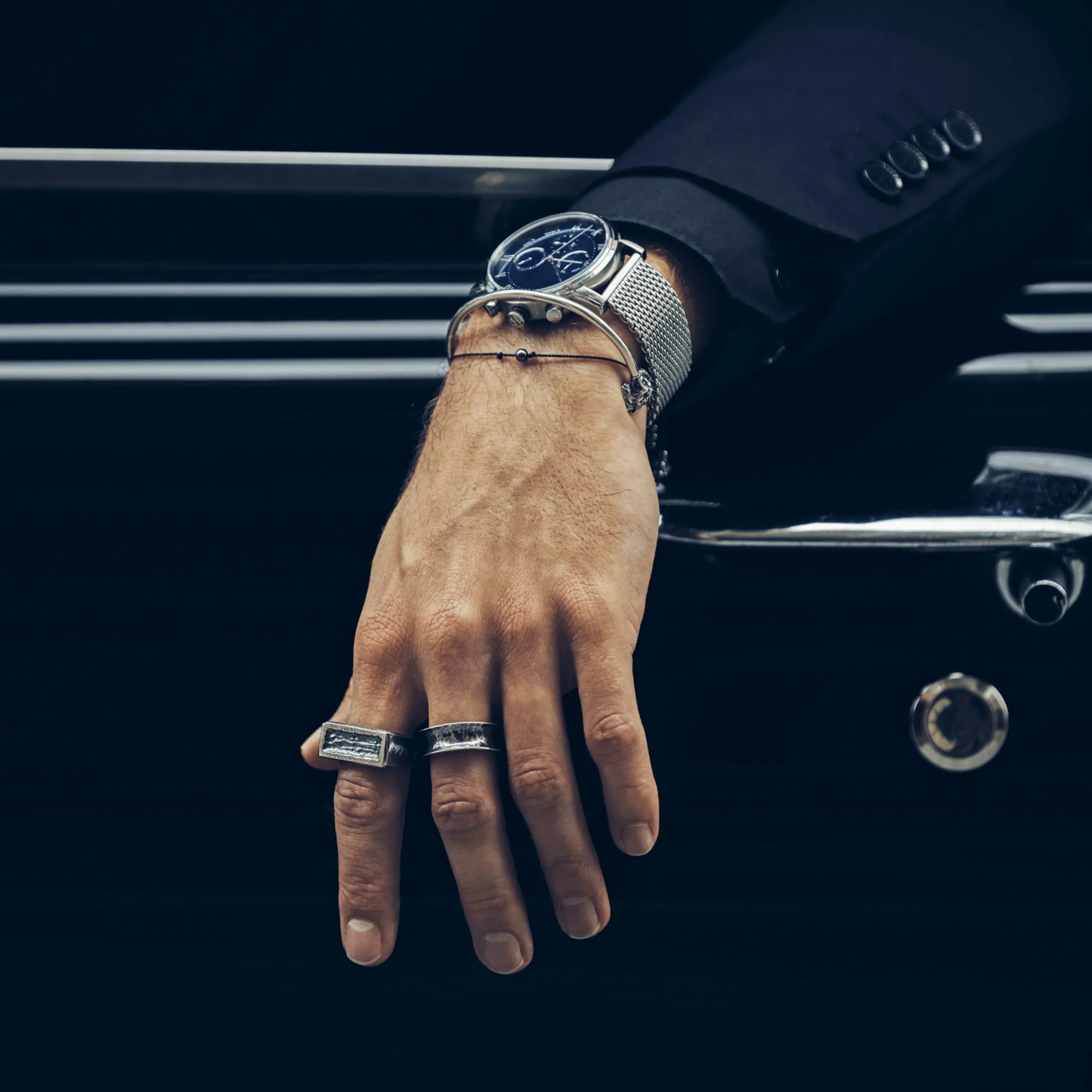 Hand wearing a watch with a car in the background