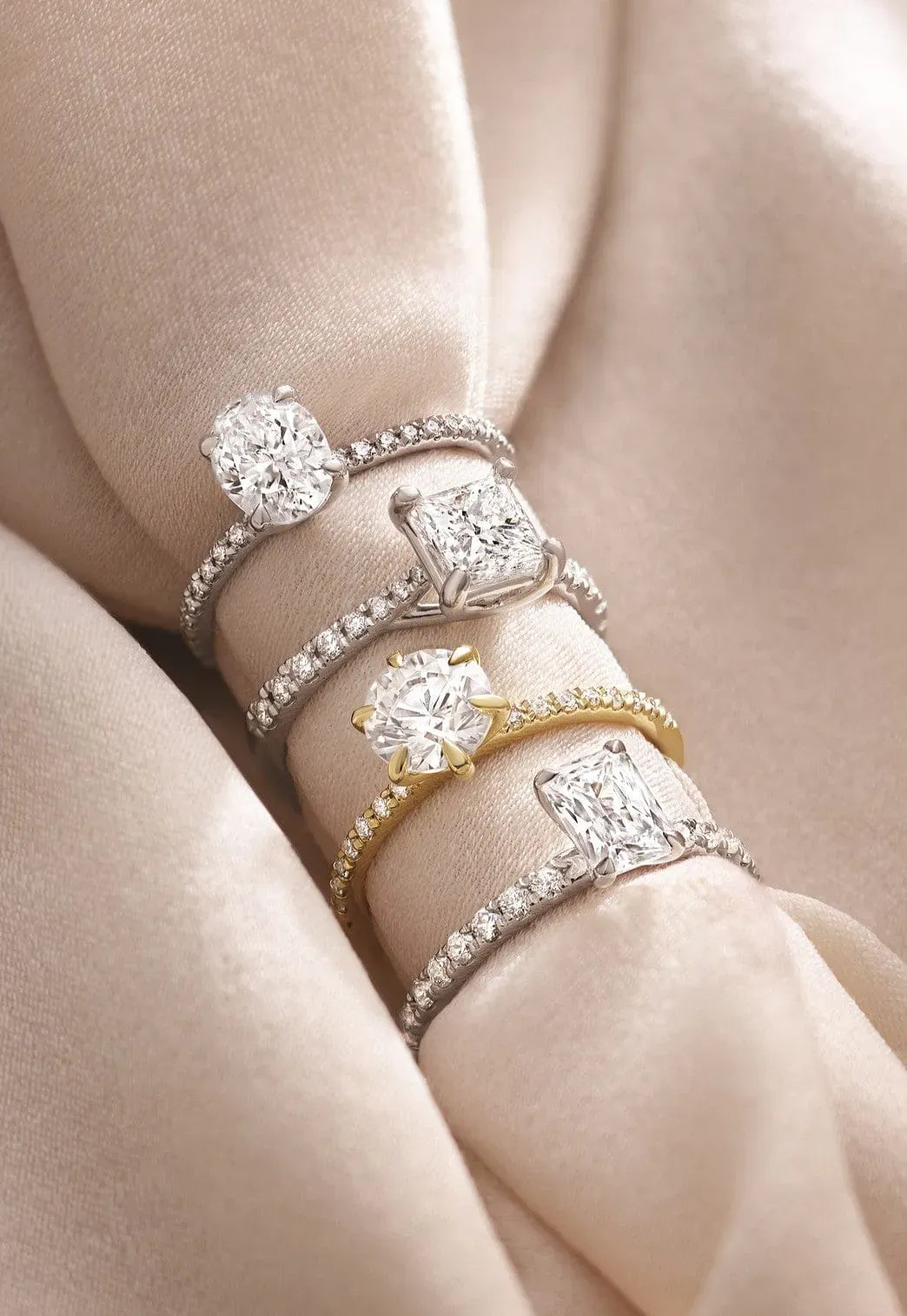 Set of pave band engagement diamond rings on a soft beige background