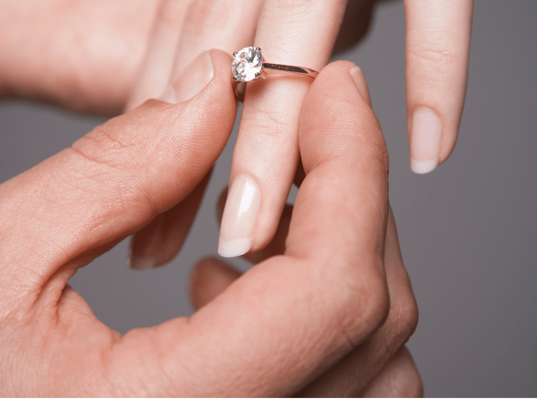 man sliding ring on womn's finger