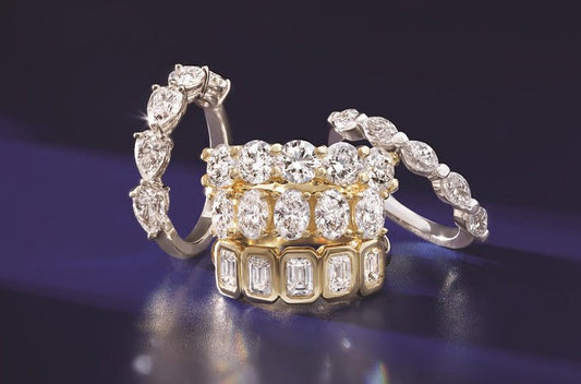 Stacked diamond anniversary bands featuring various cuts and settings, highlighting custom jewelry design and in-house consultation.