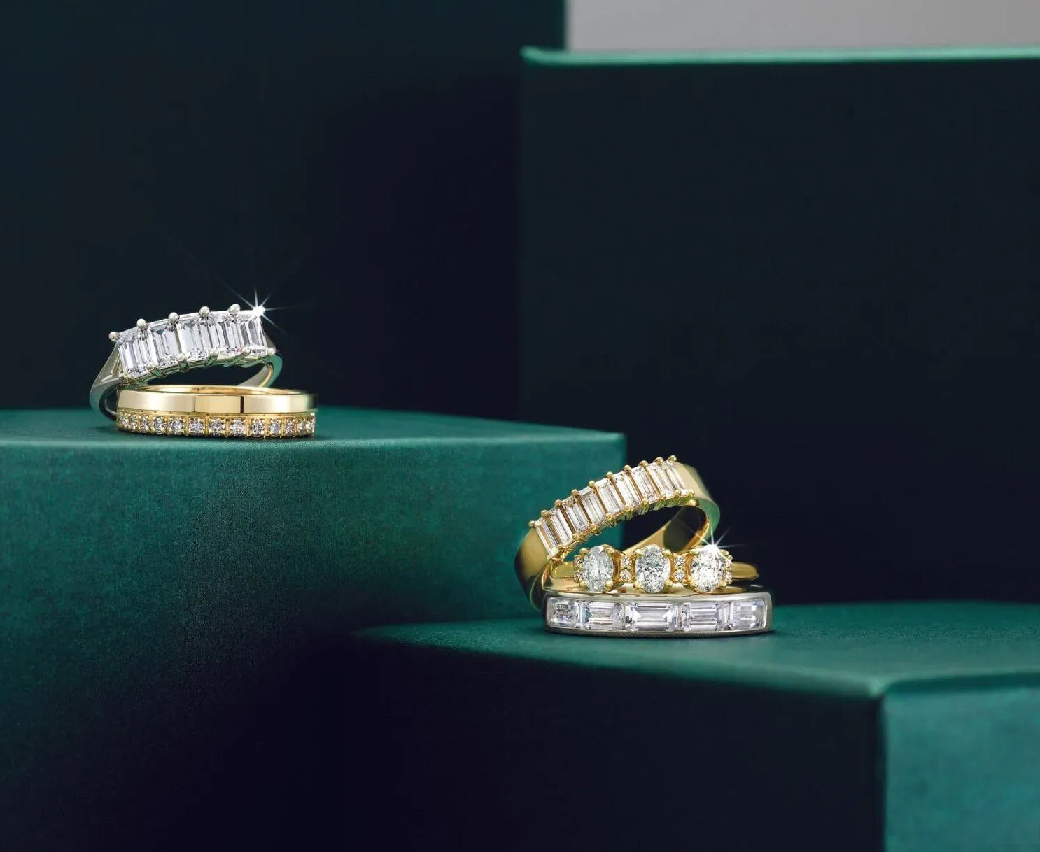 Gold and diamond rings on a green surface with a dark background