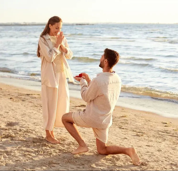 Man proposing to a woman on a beach with ocean in the background
