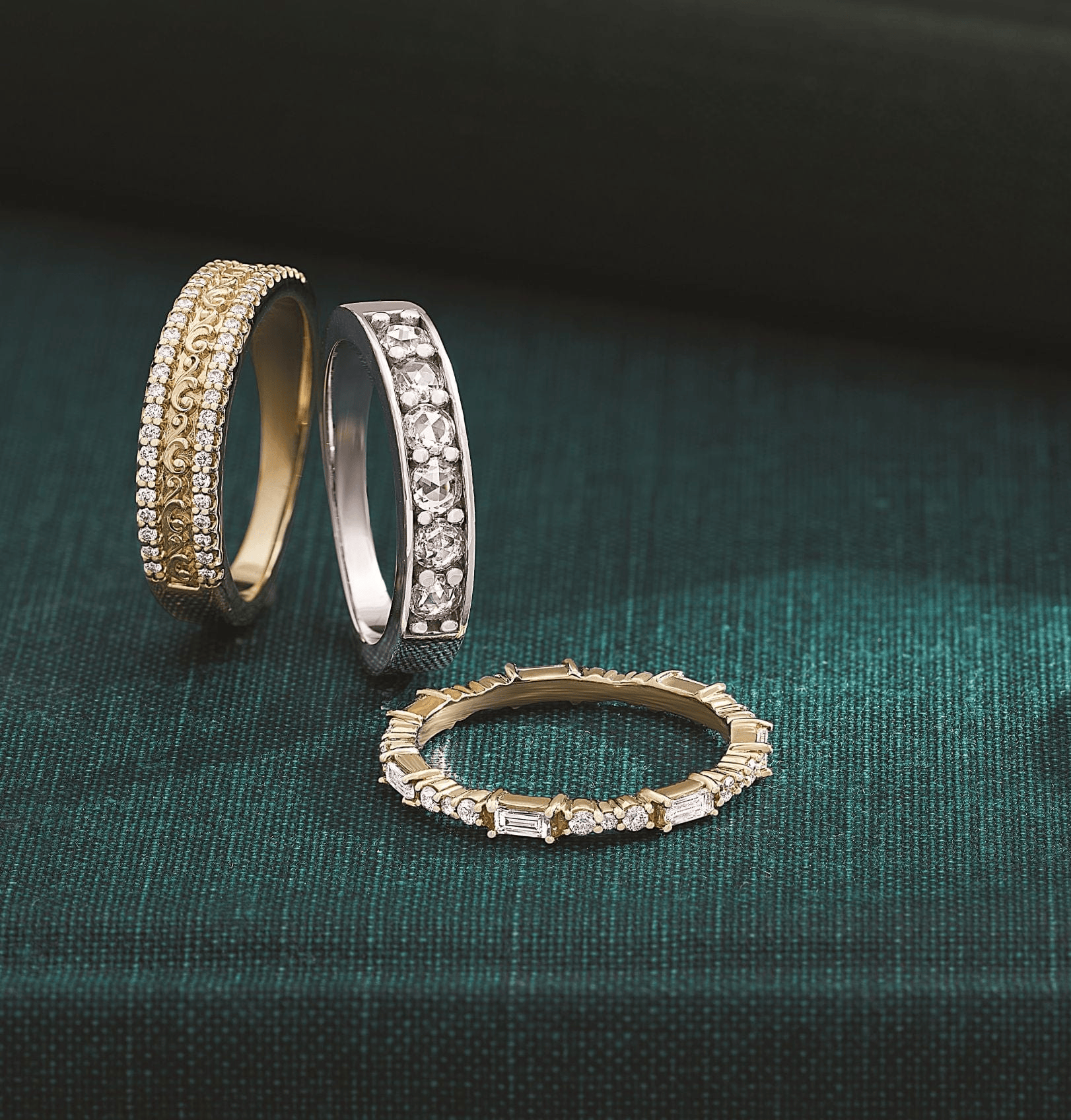 Three diamond rings on a dark green fabric background